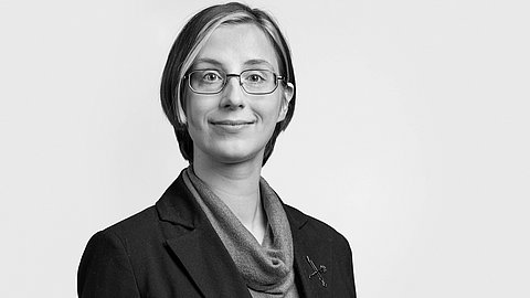 Schwarz-weißes Portrait von Nadja Mozdzen vor grauem Hintergrund