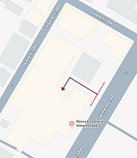 Schematischer Plan der Mensa Wilhelmstraße mit umliegenden Straßen; ein dunkelroter Pfeil zeigt den Fußweg von der Wilhelmstraße (Gebäudeseite), der zur Rückseite des Gebäudes führt.