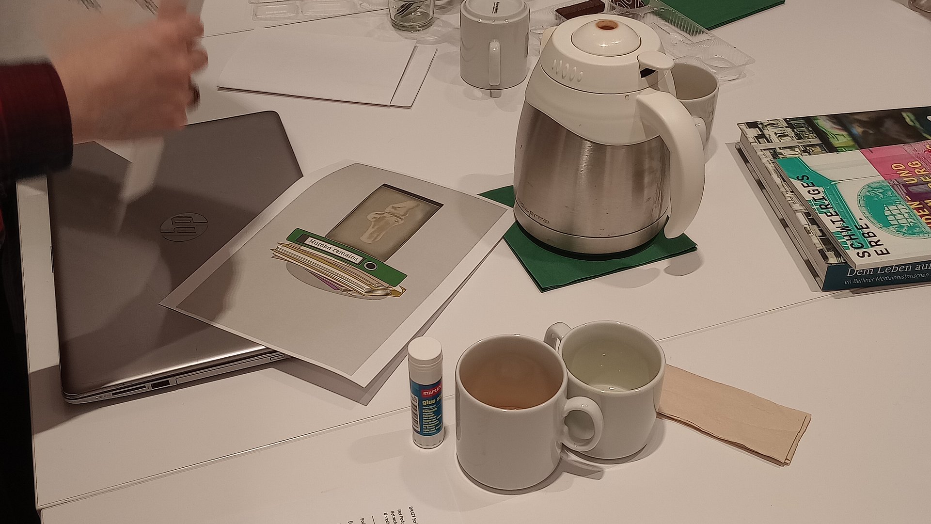 Foto: MUT | Nadja Mozdzen Voller Arbeitstisch mit Notizzetteln, Ausdrucken und Kaffeebechern