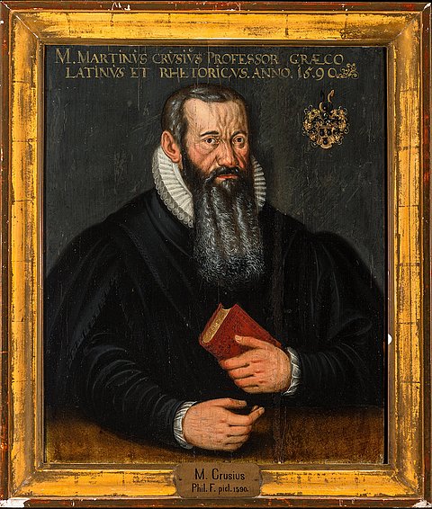 Gold gerahmtes, historisches Portrait von einem dunkel gekleideten Mann mit langem, grau-schwarzem Bart, der ein rotes Buch vor der Brust hält