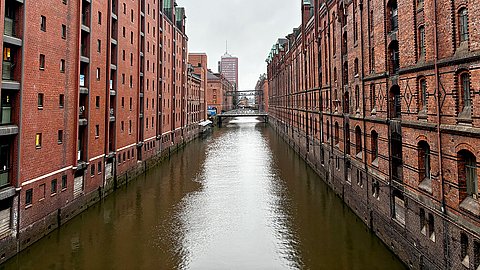 Blick auf einen Kanal der Speicherstadt in Hamburg, mit aufragenden roten Backsteingebäuden zu beiden Seiten