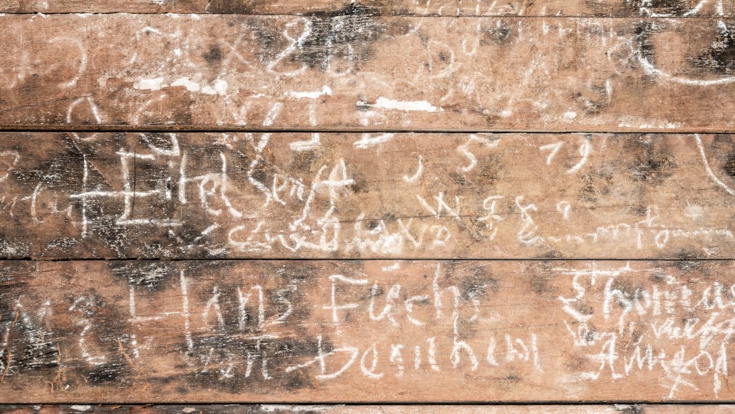 Holzbohlen der Innenwand, mit Kreide bekritzelt