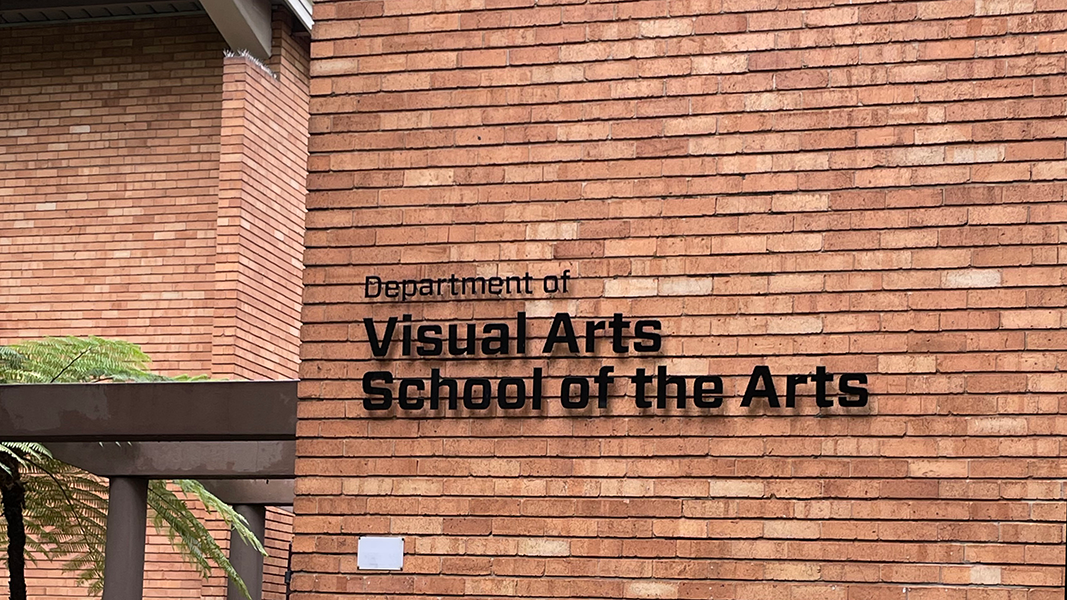 Ecke eines roten Backsteingebäudes mit den schwarzen Metalllettern "Department of/Visual Arts/School of the Arts"