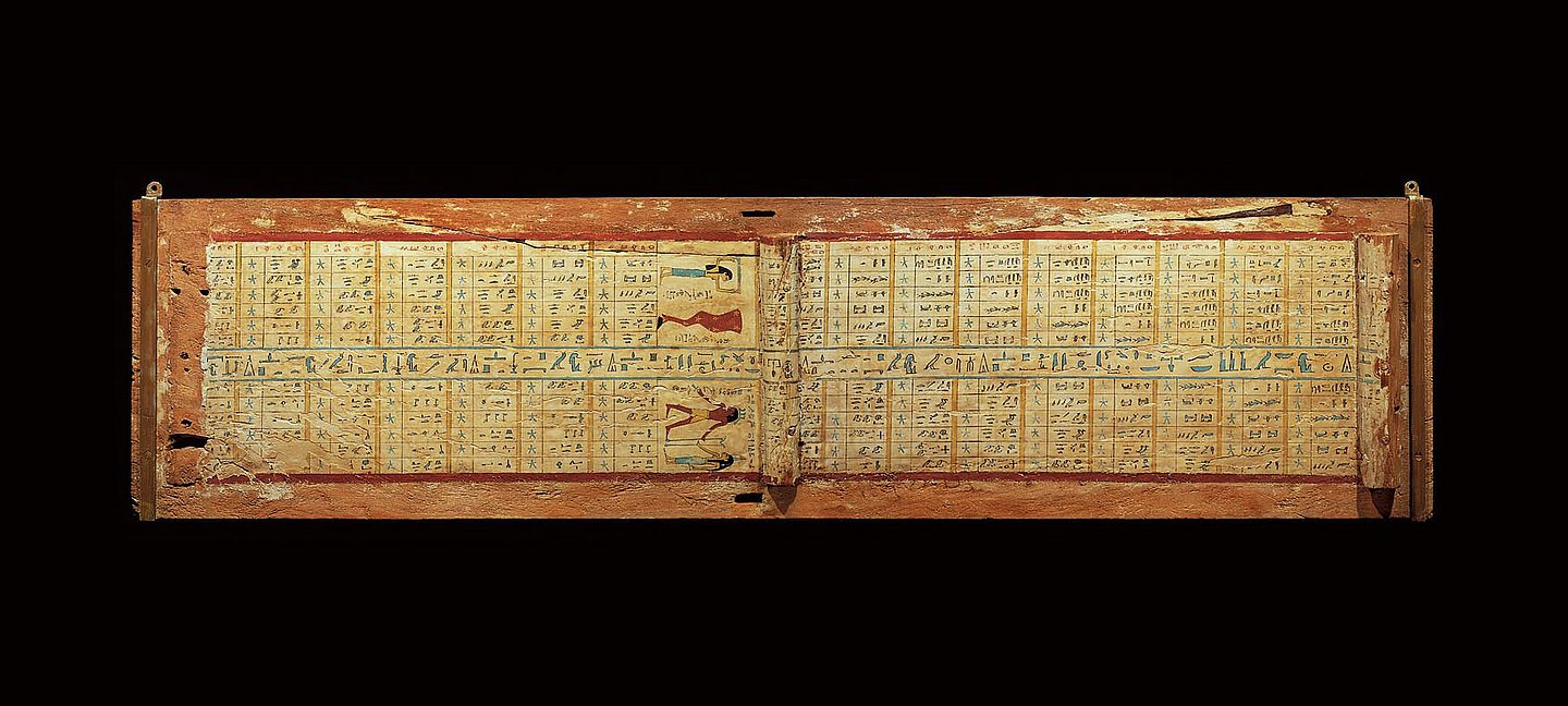 Foto: MUT Mit hieroglyphischer Inschrift bedeckter Sargdeckel aus Holz vor schwarzem Hintergrund