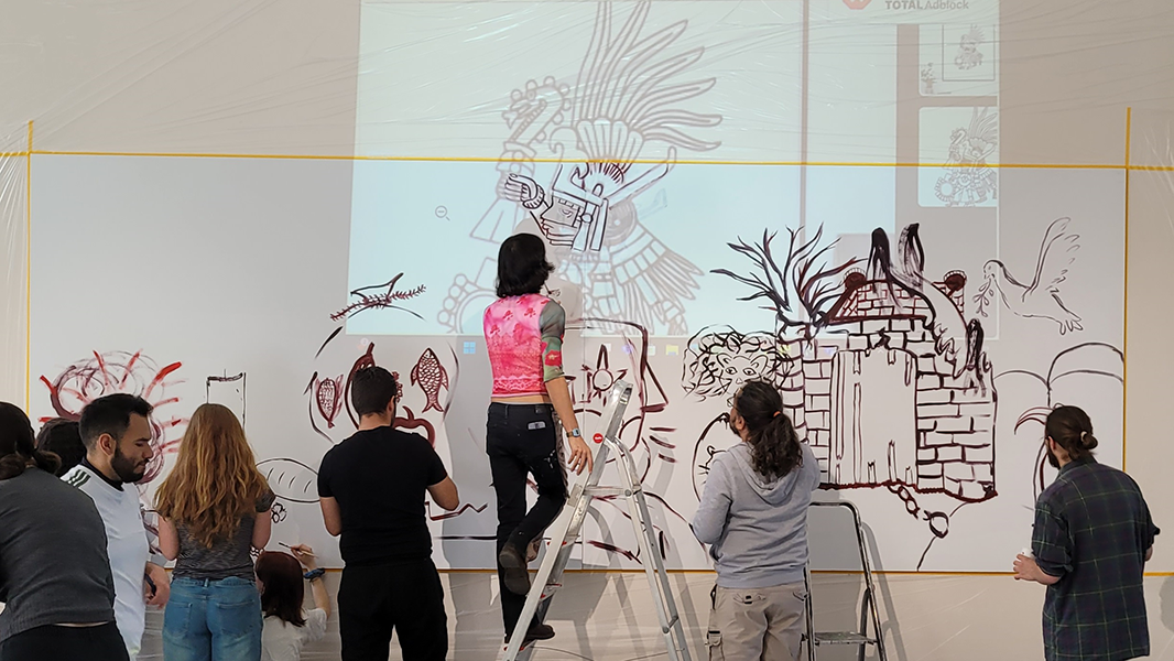 Foto: MUT | Ernst Seidl Studierende der Spring School 2025, teils auf einer Trittleiter, die eine Projektion südamerikanischer Kunst auf einer Wand abzeichnen