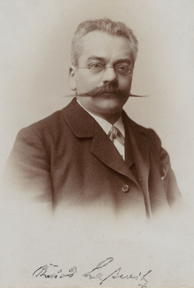 Sepiafarbenes Portrait eines Mannes mit kurzen Haaren, rundlichem Gesicht und breitem Schnauzbart. Darunter der Name "Kurd Laßwitz" in Kurrentschrift